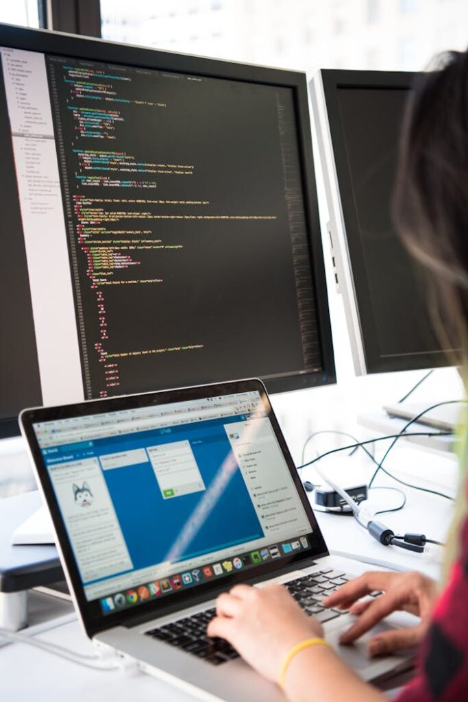 The Art of Drawing Readers In: Your attractive post title goes here Programmer working on code across multiple screens in a modern office setting.